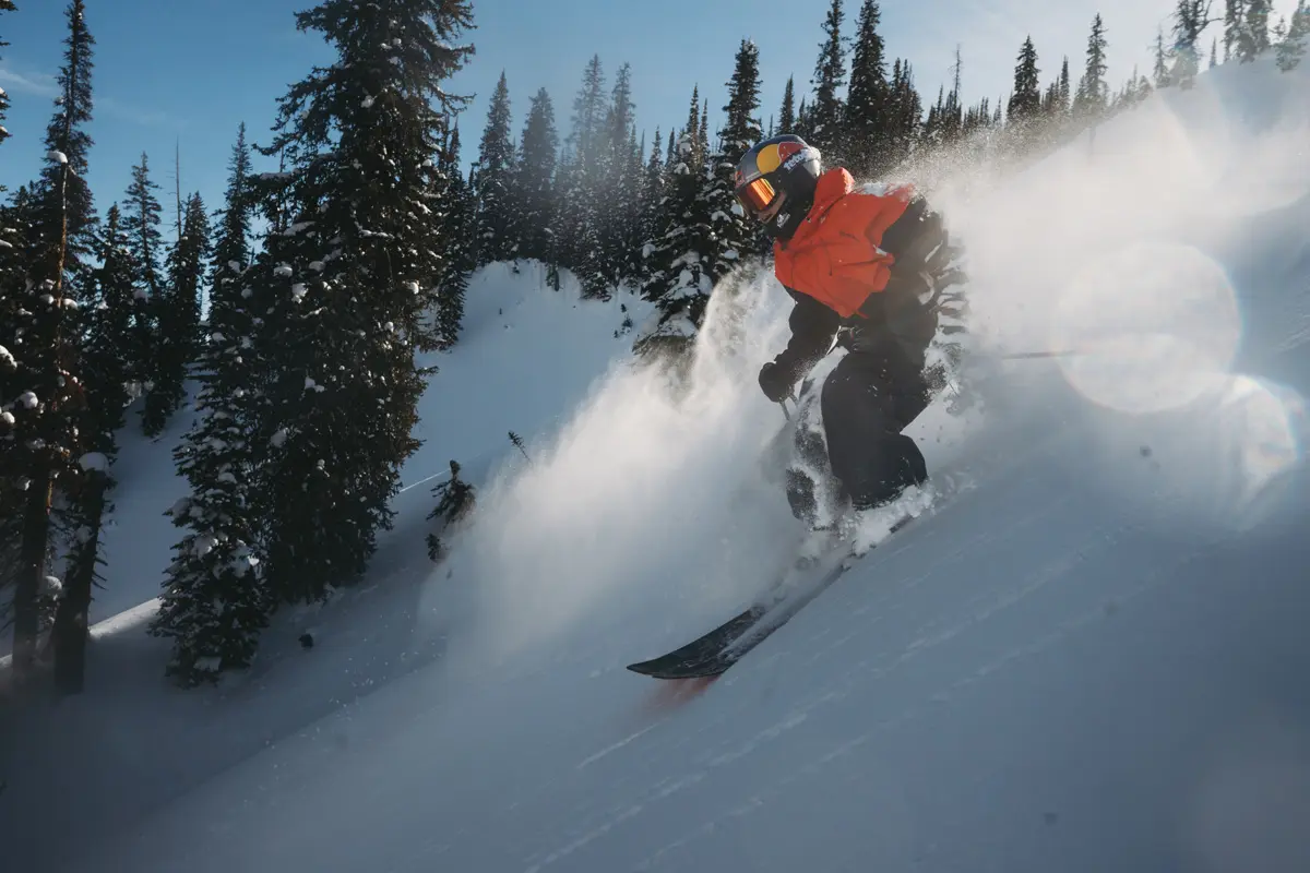 A skier in a red jacket and helmet glides quickly down a snowy, tree-lined slope, kicking up a spray of powder under a clear blue sky. Mt. Rose Ski Tahoe A skier in a red jacket and helmet glides quickly down a snowy, tree-lined slope, kicking up a spray of powder under a clear blue sky. Mt. Rose Ski Tahoe