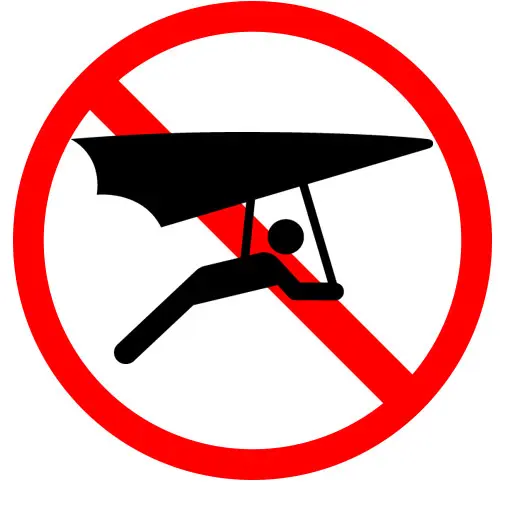 A black silhouette of a person hang gliding is overlaid with a red prohibition circle and slash, emphasizing that hang gliding is not allowed to ensure ski resort safety and protect the well-being of all guests. Mt. Rose Ski Tahoe