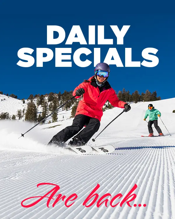 Two people skiing down a groomed snowy slope on a sunny day, with large text above reading "DAILY SPECIALS" and smaller red text below stating "Are back... Experience Ski Tahoe at its best!. Mt. Rose Ski Tahoe