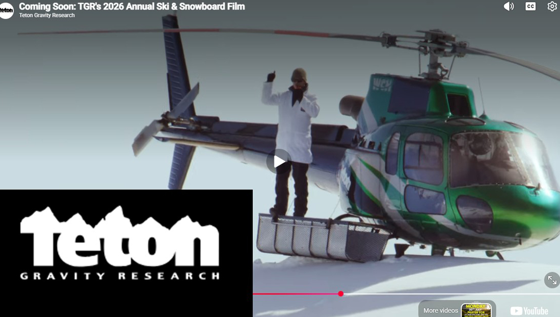 A person in a white coat and ski gear stands on a snow-covered helicopter skid, waving, with a green helicopter on a snowy mountain. Teton Gravity Research logo is visible in the corner. Mt. Rose Ski Tahoe